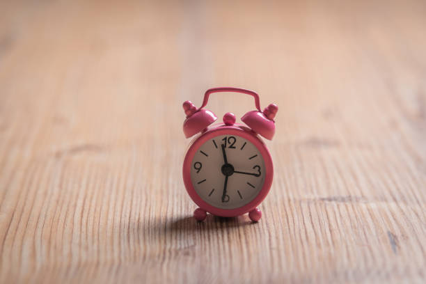 istock Pink vintage alarm clocks on wooden table 1208580752