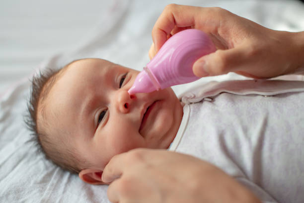 istock mother using baby nasal aspirator mucus nose suction 1208582410