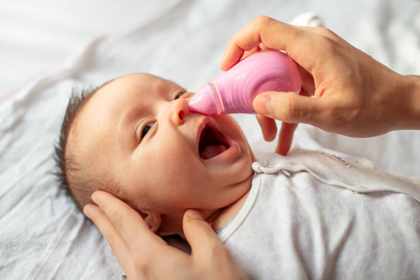 istock mother using baby nasal aspirator mucus nose suction 1208584283