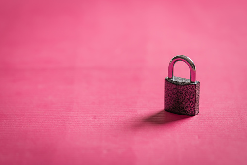 A big metal padlock on classic pink background in studio.