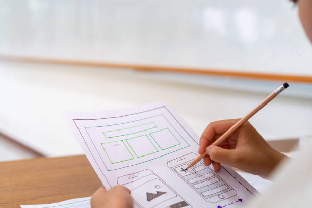 istock asian startup web app designer team creating user experience UX on smartphone layout to design applications for mobile phone on paper prototype framework production.UX UI creative design of technology 1208587726