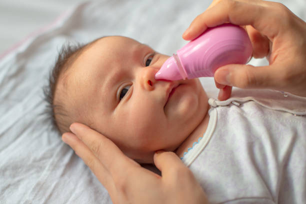 istock mother using baby nasal aspirator mucus nose suction 1208588276