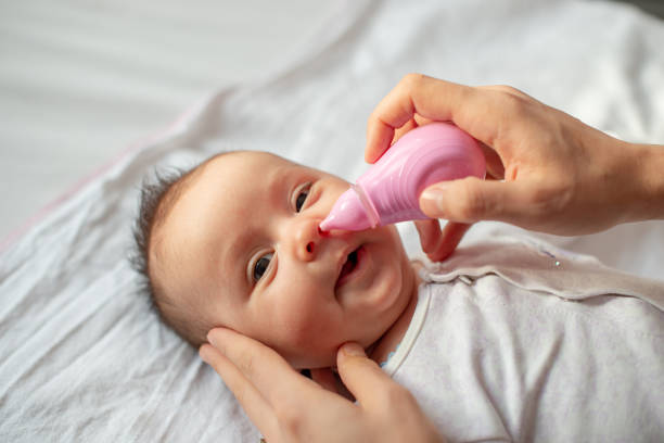 istock mother using baby nasal aspirator mucus nose suction 1208588982