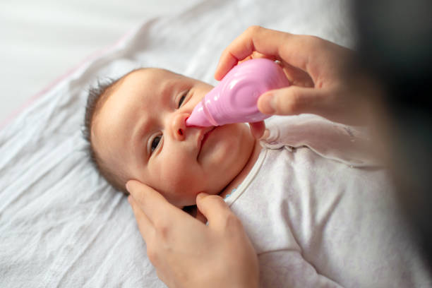 istock mother using baby nasal aspirator mucus nose suction 1208589077