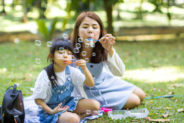 istock Mother and daughter blowing bubble together 1208589622