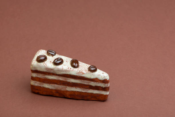 istock Piece of artificial cake, ceramic decoration on brown background. 1208589866