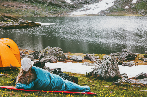 Woman relaxing in sleeping bag on mat enjoying lake landscape Travel Lifestyle camping concept adventure summer vacations outdoor hiking harmony with nature