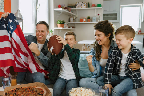 family with children watching american football game on tv - american football football food snack imagens e fotografias de stock