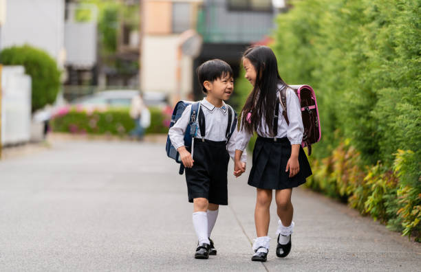 Brother and sister walking home from school together. Tokyo, Japan