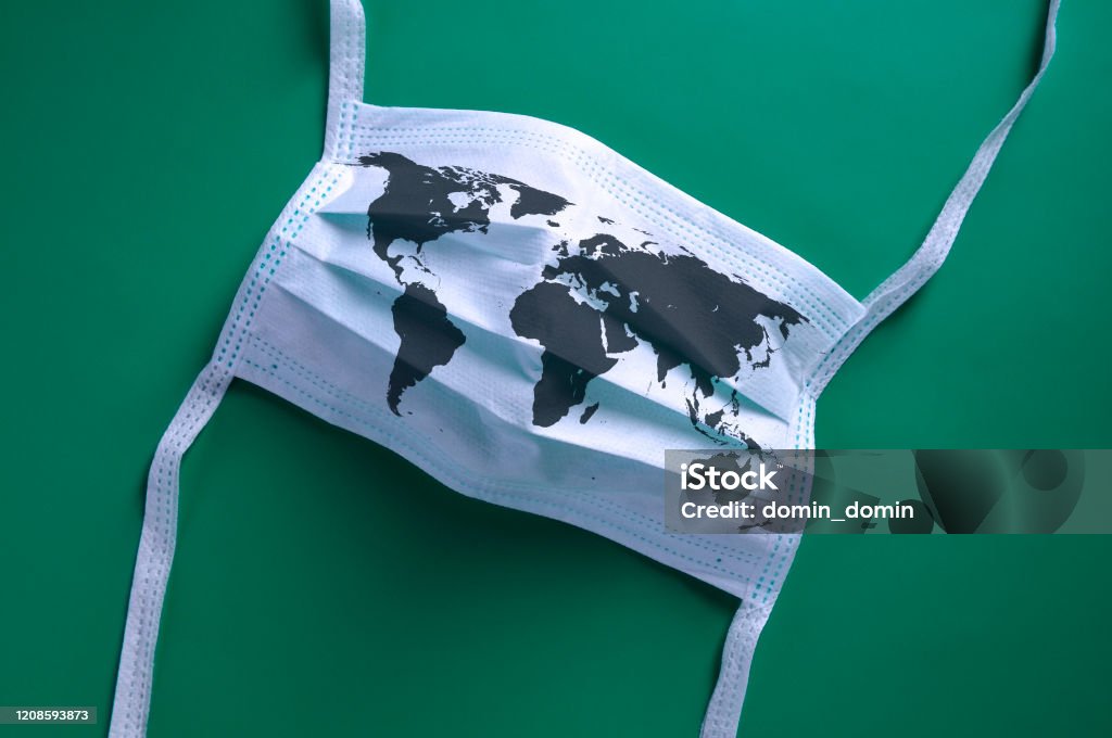 White face mask with a map of the world is lying on a green background White face mask with a map of the world is lying on a blue background. Coronavirus Stock Photo