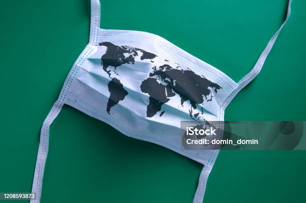 White Face Mask With A Map Of The World Is Lying On A Green Background Stock Photo - Download Image Now