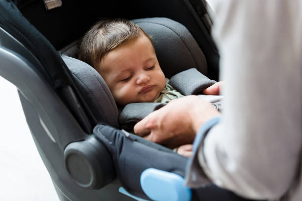 istock Dad straps baby into car seat 1208596741