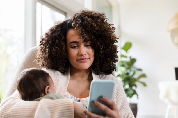 istock New mom uses smarphone at home 1208596754