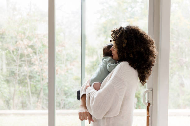 istock Mom looks through window at home 1208596801