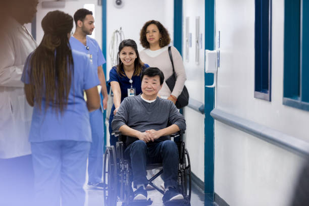 istock Cheerful nurse pushes patient in hospital hallway 1208596949