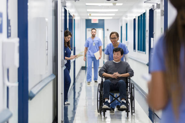 istock Cheerful nurse pushes patient in wheelchair 1208596975
