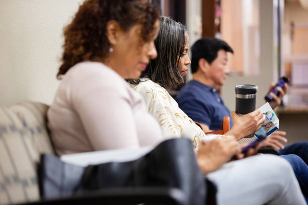 istock Three patients sit in a row against wall in waiting room 1208597144