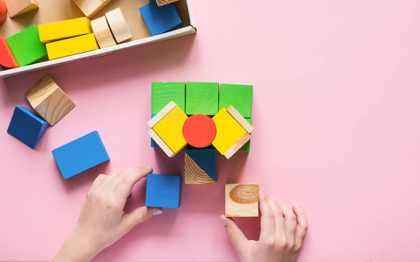 the child collects the designer builds a house of wooden cubes. toys from environmental natural materials for children. - mobile work imagens e fotografias de stock