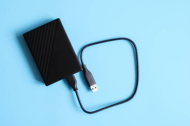 istock external hard drive black color with connection cable on blue background 1208601478