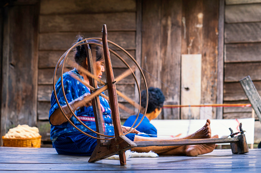Craftsmen of Thai indigo cotton. Old Woman are the original Indigo Cotton Weaving in the community of Sakon Nakhon province. Thai old woman shows weaving spinning natural colorful threads or yarn.