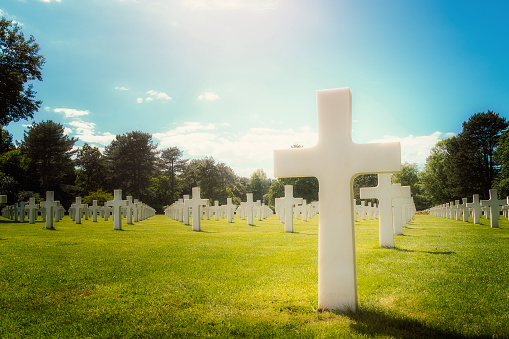 Closeup of a white cross military grave in the Normandy American Cemetery on a sunny day, Colleville-sur-Mer, France. With copy space.