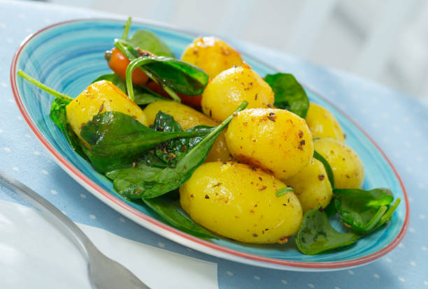 Image of delicious cooked fried new potatoes with spinach served at plate