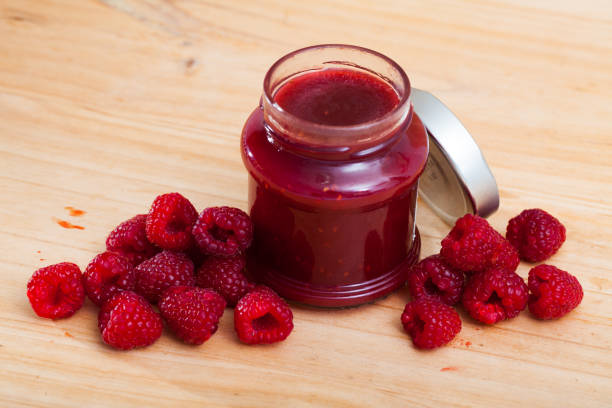 istock Image of tasty  raspberry jam in jar and fresh  berries on wooden surface 1208607115