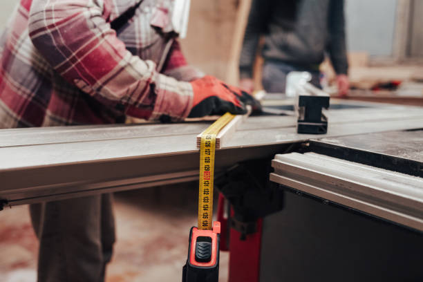istock Worker in a carpentry shop measures plywood for cutting 1208608593