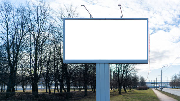 istock Advertising billboard metal, large horizontal. Behind a park with trees. With white margin for mock-up posters 1208610095