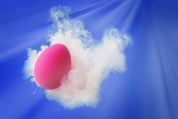 istock Pink egg in ink water splash and rays of light over blue background 1208610385