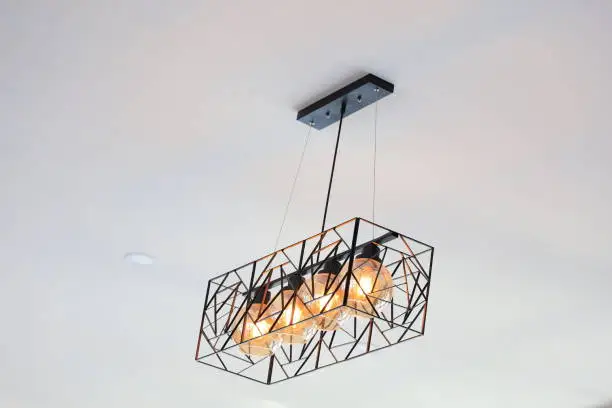 Photo of modern lamp on white ceiling