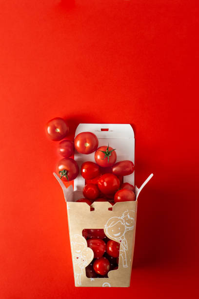 istock Sweet cherry tomatoes in papar take out box on orange red background with copy space 1208612124
