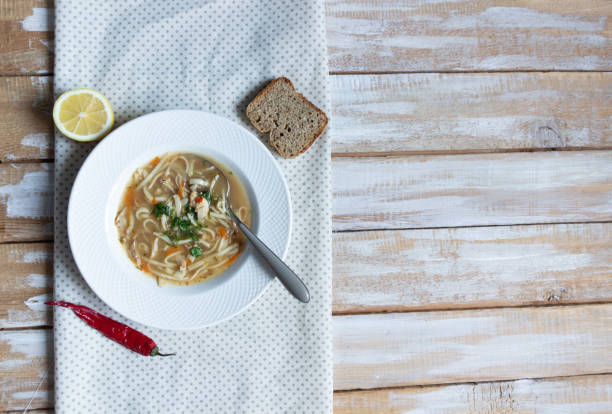 istock plate of noodle soup with chicken, red pepper, lemon, bread, spoon on rustic background 1208612590