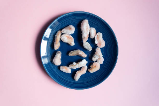 istock Frozen shrimps in ice on blue blate on pink background 1208612670