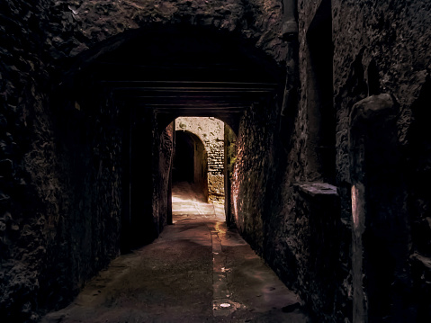Medieval street / tunnel in Cervera, Spain. Inside a narrow dark stone cave, view of the door