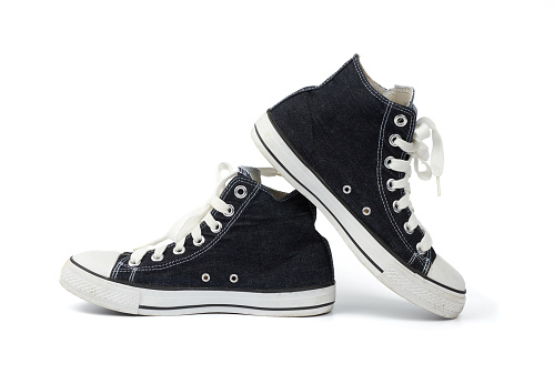 pair of black textile sneakers with white laces isolated on a white background, shoes are sideways