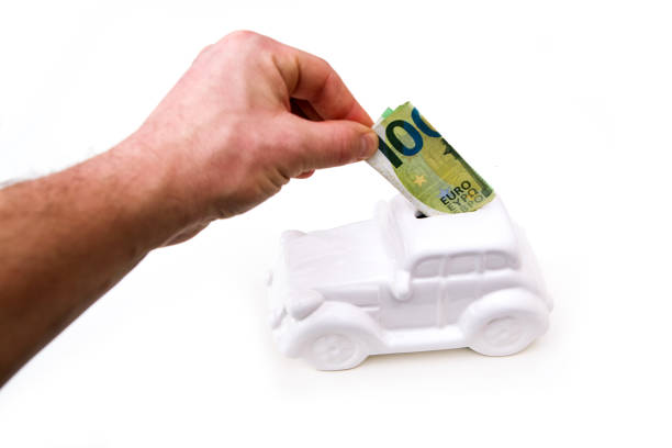 istock The hand is puting a banknote into the ceramic car shaped money box. 1208618611