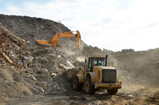 istock Industrial waste treatment plant. Excavator and a front-end loader work at landfill with concrete demolition waste 1208618965