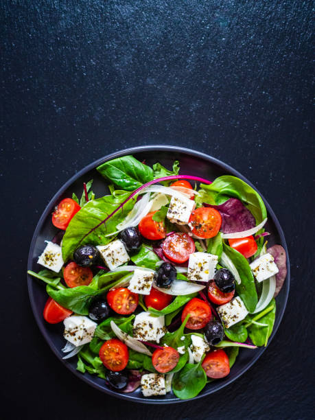 istock Greek salad on black stone background 1208619087