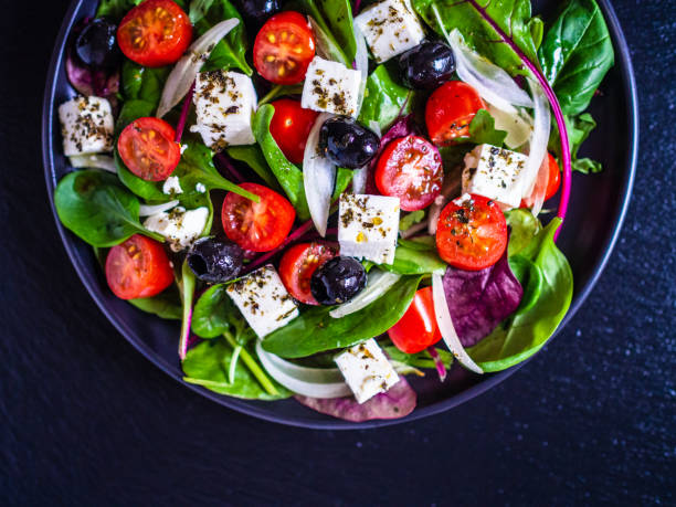 istock Greek salad on black stone background 1208619117