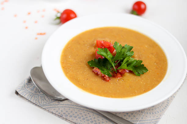 istock Vegetable soup with lentils on a white background. Served with chopped cherry tomatoes and herbs. Nearby are pieces of ciabatta. Raw groats in the background. Vegetarian dish. 1208620120
