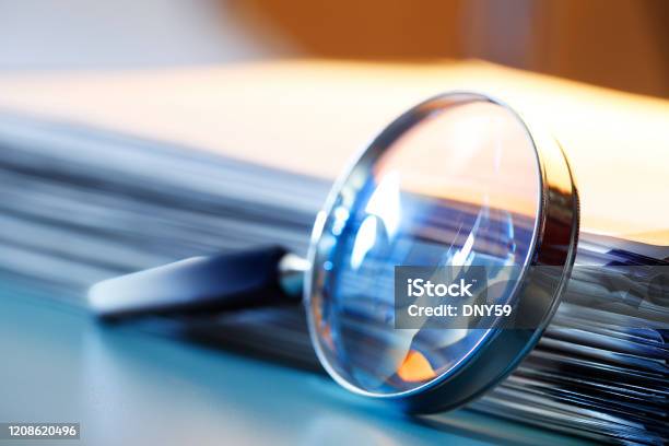 Magnifying Glass Leaning Against Stack Of Papers Stock Photo - Download Image Now - Magnifying Glass, Document, Research