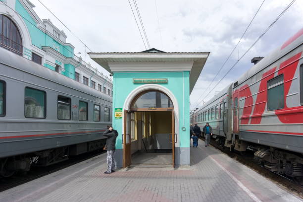 Omsk, Omsk Region / RF - April 21, 2015: The passenger leaves the underpass to the platform between two standing trains at the railway station.