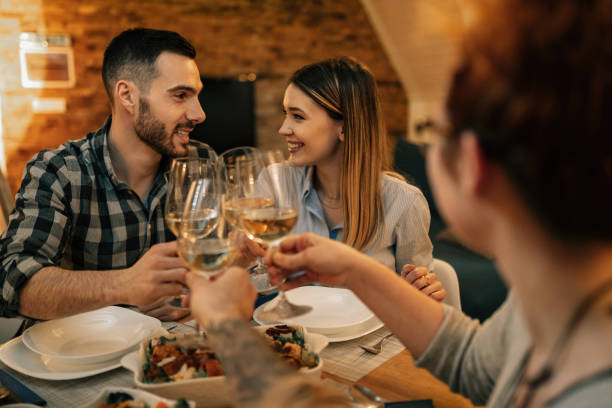 istock Young happy couple toasting with wine while having dinner with friends. 1208623807