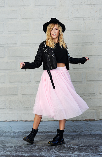 Pretty trendy blond girl posing in black leather jacket and pink tulle skirt