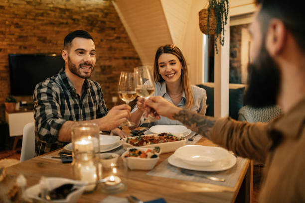 istock Young happy friends toasting with wine during dinner in dining room. 1208625710