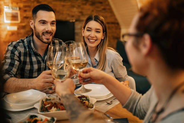 istock Happy couple toasting with friends at dining table. 1208626496