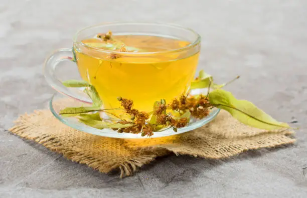 Photo of cup of tea from linden flowers on a gray background. The concept of healthy teas