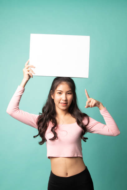 istock Young Asian woman point to blank sign. 1208628669