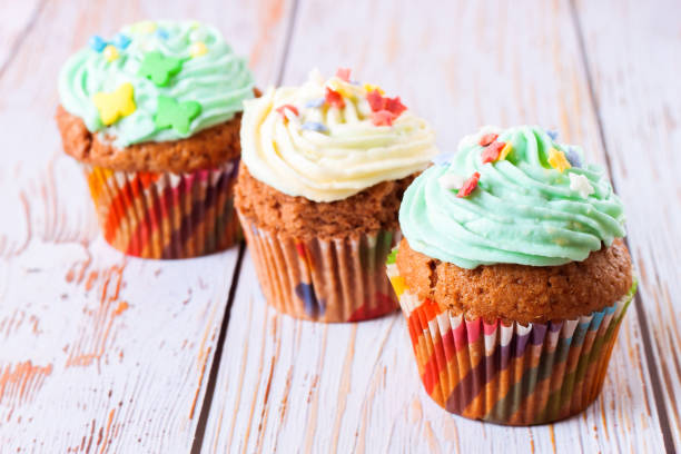 istock Colorful cupcakes on a white wooden background 1208628800